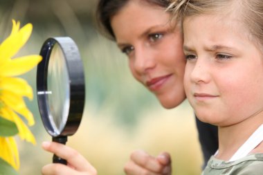 Girl with magnifying glass watching flower clipart