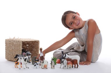 Little girl playing with farm animal toys clipart