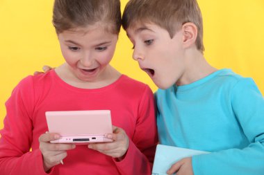 Brother and sister playing hand-held video games clipart