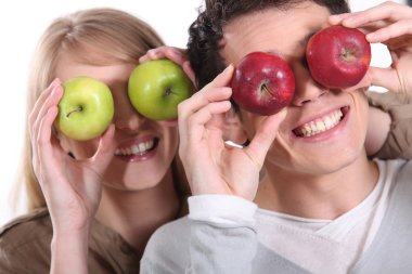 Couple holding up apples to their eyes clipart