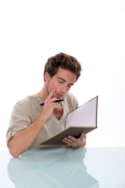 Pensive man writing in book clipart