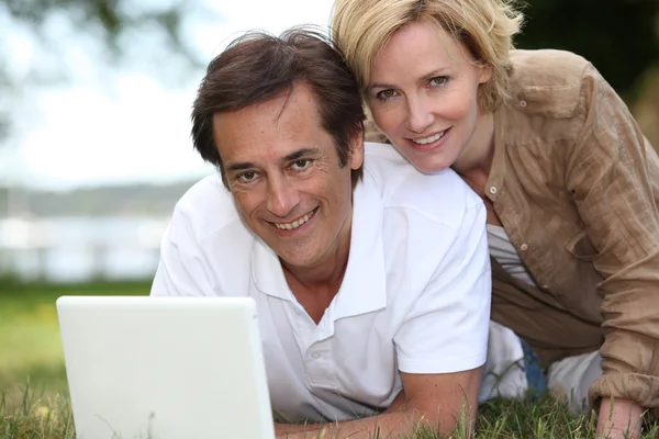 Par på gräs med dator — Stockfoto