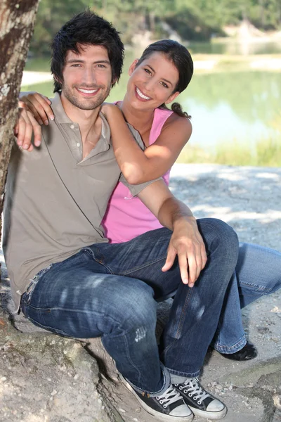 Couple sitting on the edge of a pond — Stock Photo, Image