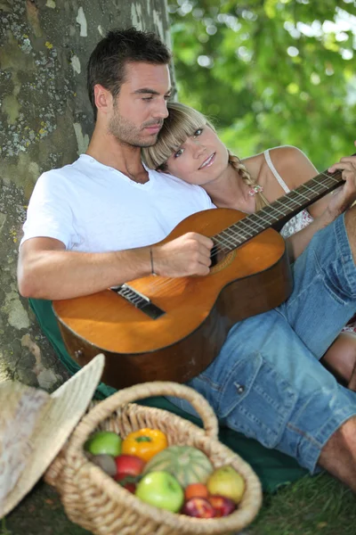 Pareja con guitarra en el campo — Foto de Stock