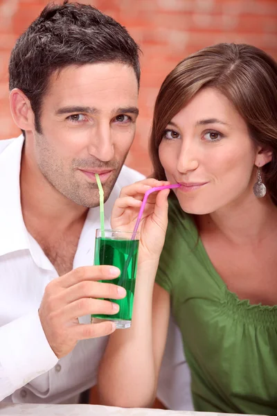 Пара пьет один и тот же коктейль — стоковое фото