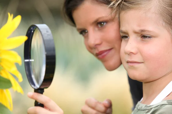Girl with magnifying glass watching flower