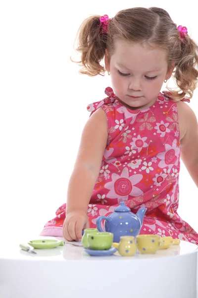 Κοριτσάκι παίζει με μοντέλο τσαγιέρα και κούπες — Φωτογραφία Αρχείου