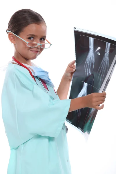 Liten flicka klädd hospital scrubs och undersöka en xray — Stockfoto
