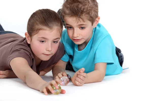 Irmão e irmã brincando com mármores — Fotografia de Stock