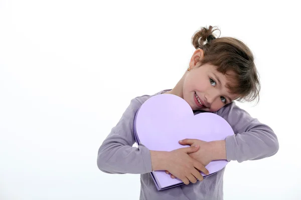 Маленькая девочка держит подарок лук в форме сердца — стоковое фото