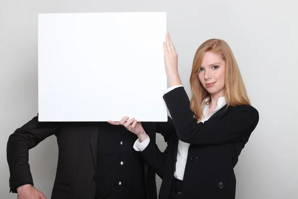 Homme d'affaires et femme d'affaires tenant un panneau publicitaire — Photo