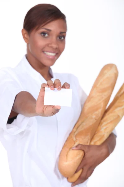 Female baker holding baguettes and a blank business card — Stock Photo, Image