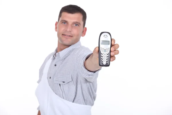 Dark haired man holding out mobile telephone — Stock Photo, Image