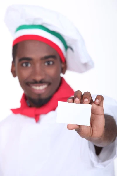 Jovem cozinheiro italiano preto mostrando um cartão profissional — Fotografia de Stock