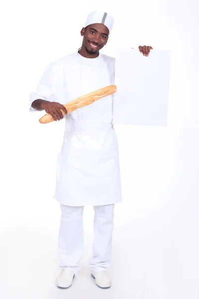 Bakery worker holding baguette and poster — Stock Photo, Image