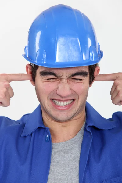 Trabalhador colocando os dedos em seus ouvidos para bloquear o ruído — Fotografia de Stock