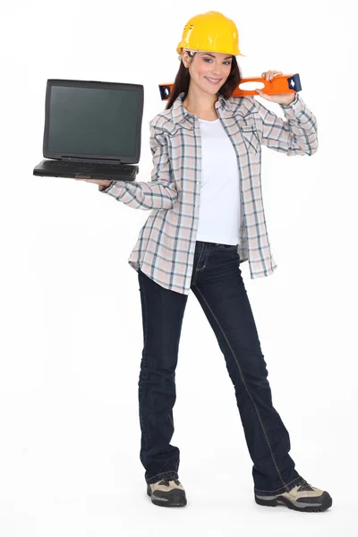 En kvinnlig byggnadsarbetare som innehar en laptop. — Stockfoto