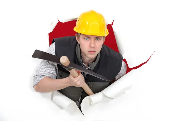 Man with pick-axe tearing through poster — Stock Photo, Image