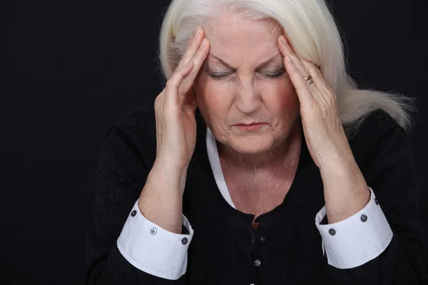 Mujer mayor que sufre de un dolor de cabeza —  Fotos de Stock