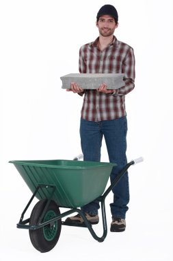 Mason placing brick in wheelbarrow clipart