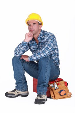 Tradesman sitting on toolchest isolated on white clipart