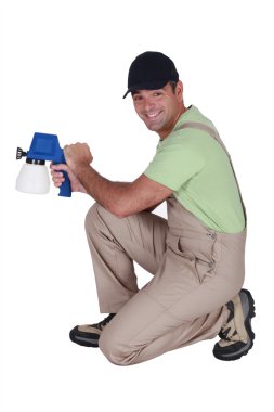 Man kneeling with paint sprayer clipart