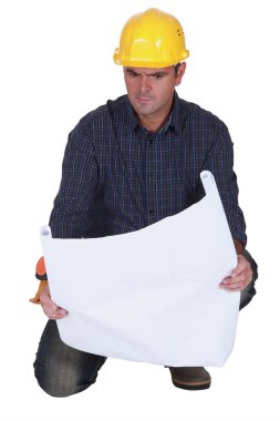 Angry tradesman looking at a technical drawing clipart