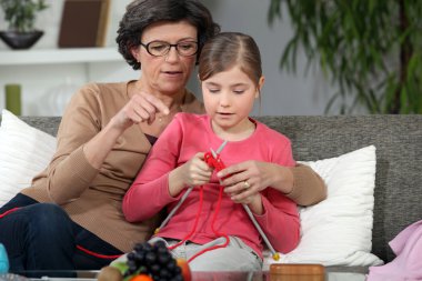 Woman teaching how to knit to little girl clipart