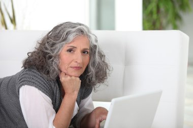 Woman lying on couch with computer clipart