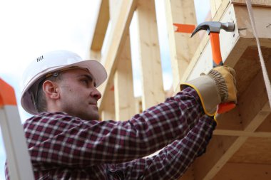 Housebuilder using a hammer clipart