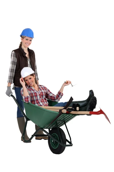 Construtora feminina carregando seu colega em um carrinho de mão — Fotografia de Stock