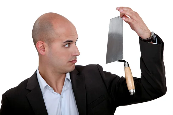 Businessman looking disbelievingly at a trowel — Stock Photo, Image
