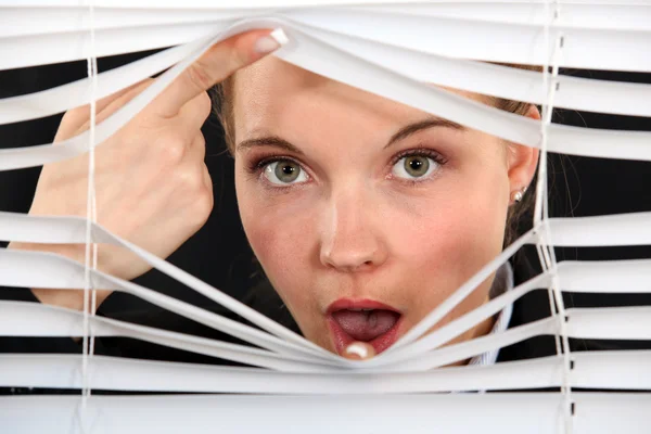 Nosy blond kvinna tittar fram genom persienner — Stockfoto