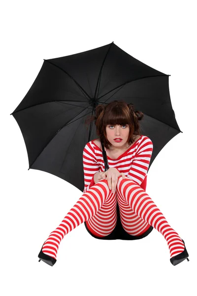 Sexy brunette in gestreepte kleding zittend op de vloer met paraplu — Stockfoto