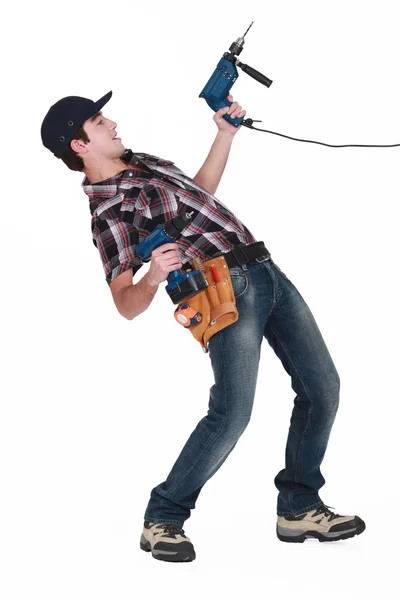 Young man pulling a drill on white background — Stock Photo, Image