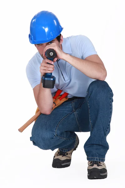 A man using his drill as a gun. — Stock Photo, Image