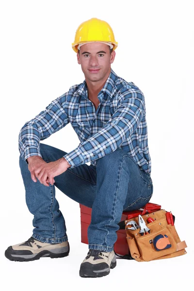 Um trabalhador da construção civil sentado na sua caixa de ferramentas . — Fotografia de Stock