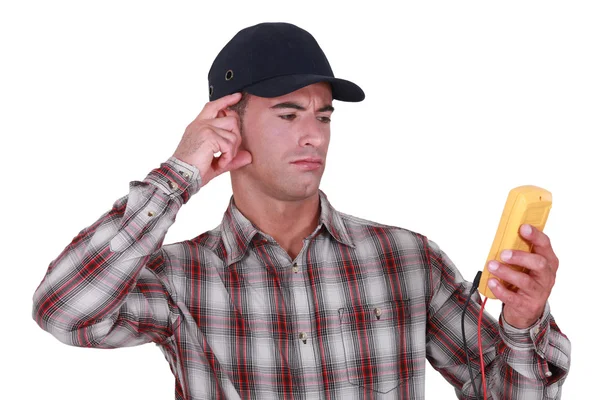 Puzzled tradesman staring at his multimeter — Stock Photo, Image
