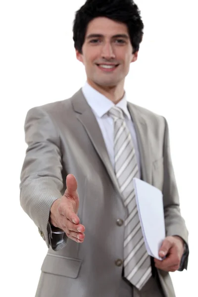 Jovem empresário todos sorrisos apertando as mãos com parceiro de negócios invisível — Fotografia de Stock