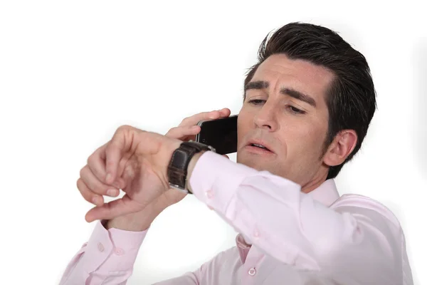 Affärsman talar på sin cell och tittar på sin klocka — Stockfoto
