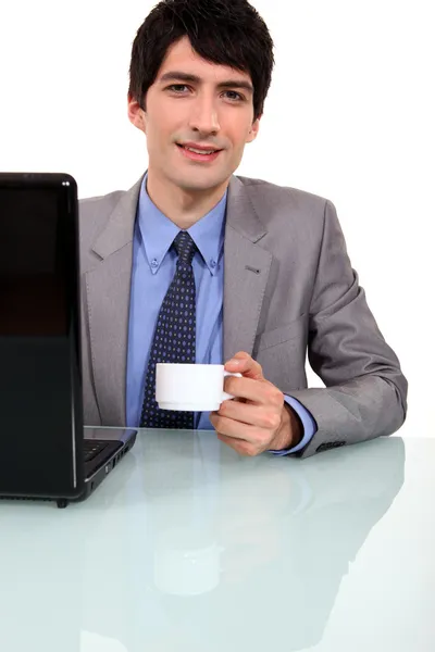 Arbetstagaren dricker kaffe framför laptop — Stockfoto