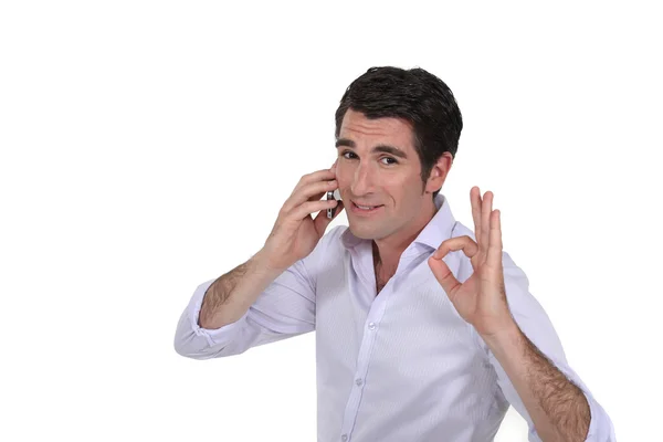 Бизнесмен делает ОК жест во время телефонного разговора — стоковое фото