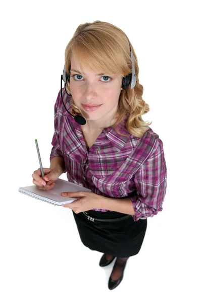 Sekretärin mit Headset macht sich Notizen — Stockfoto