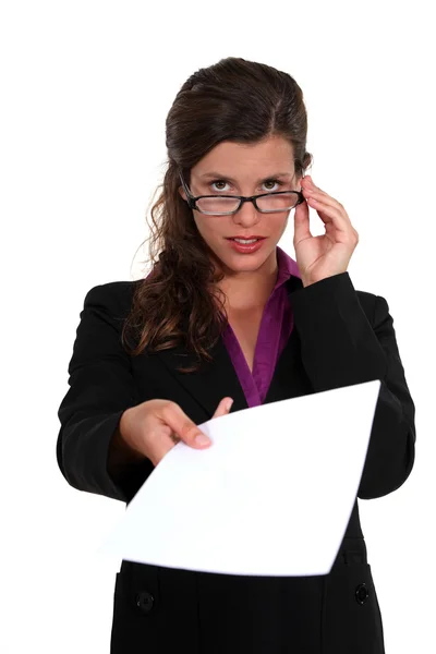 Επιχειρηματίας, ανταλλαγής κίνησης πάνω από τα γυαλιά της και κρατώντας ένα έγγραφο — Φωτογραφία Αρχείου