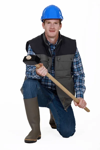 Uomo inginocchiato con martello e stivali wellington — Foto Stock
