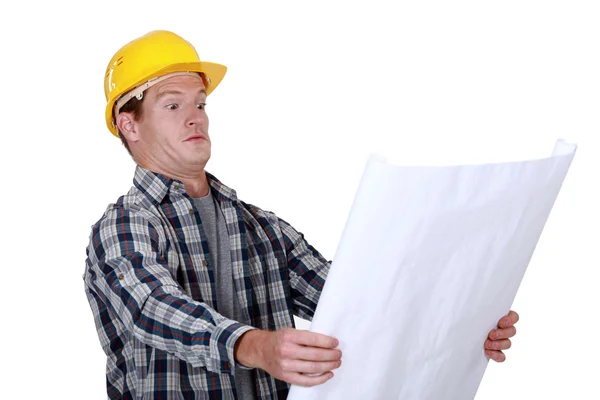 Handwerker hält einen Bauplan in der Hand und wirkt sehr überrascht — Stockfoto