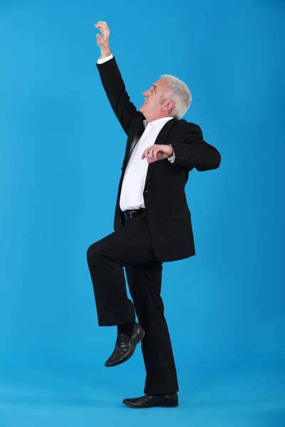 Geschäftsmann klettert auf blauem Hintergrund — Stockfoto