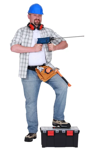 Hombre sosteniendo taladro eléctrico y apoyando el pie en la caja de herramientas —  Fotos de Stock
