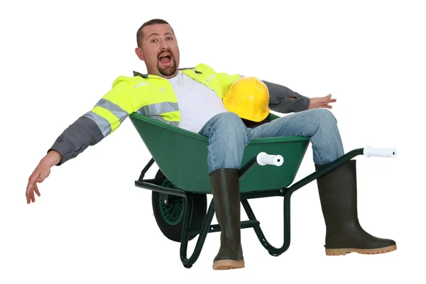 Goofy tradesman sitting in a wheelbarrow — Stock Photo, Image