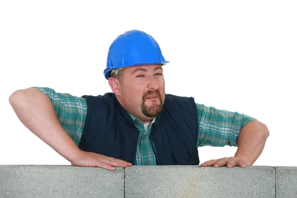 Pedreiro expressivo atrás da parede de tijolo — Fotografia de Stock